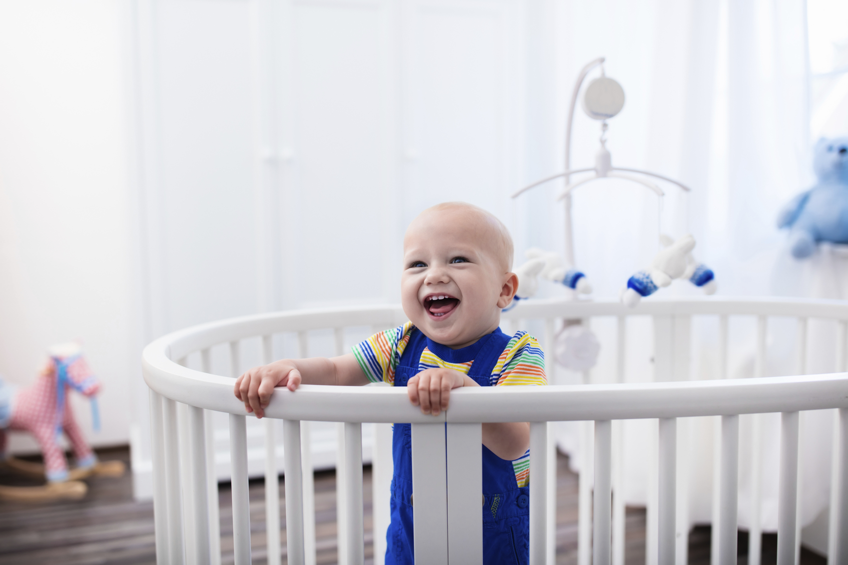 Laughing baby boy standing in bed