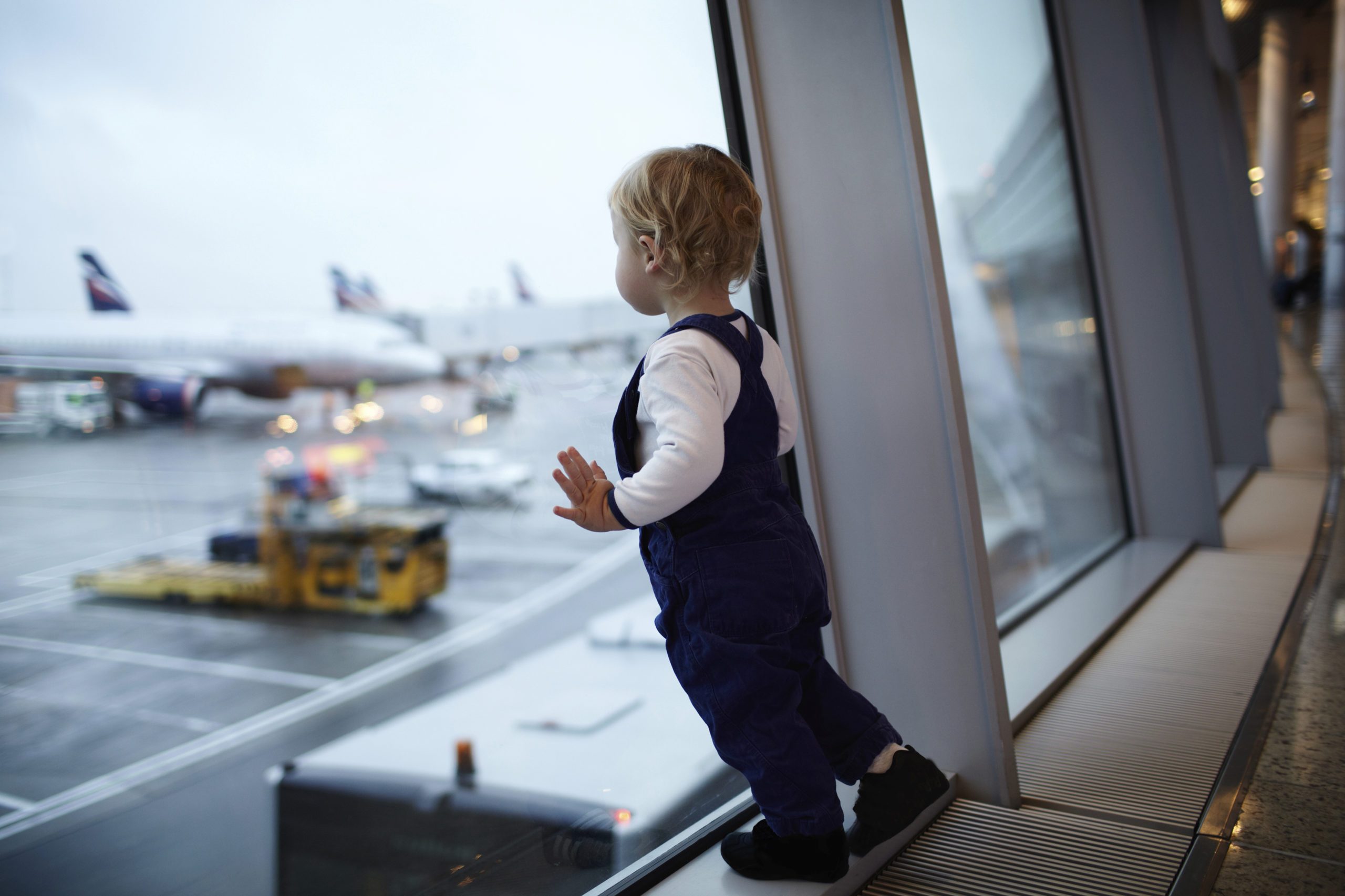 Kid near the window in the airport.